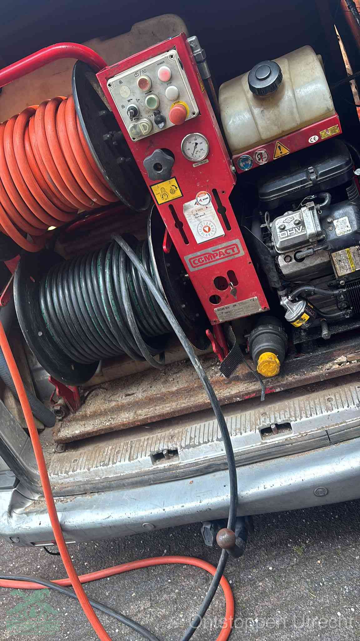 Een rood hogedruk-rioolreinigingstoestel in de laadbak van de bedrijfsbus, apparatuur voor een hardnekkige afvoerverstopping in Utrecht