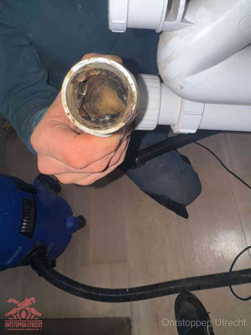 Een losgekoppelde afvoerbuis die van binnen volledig is dichtgeslibd met vet en aanslag, de meest voorkomende oorzaak van een verstopte gootsteen in Utrecht