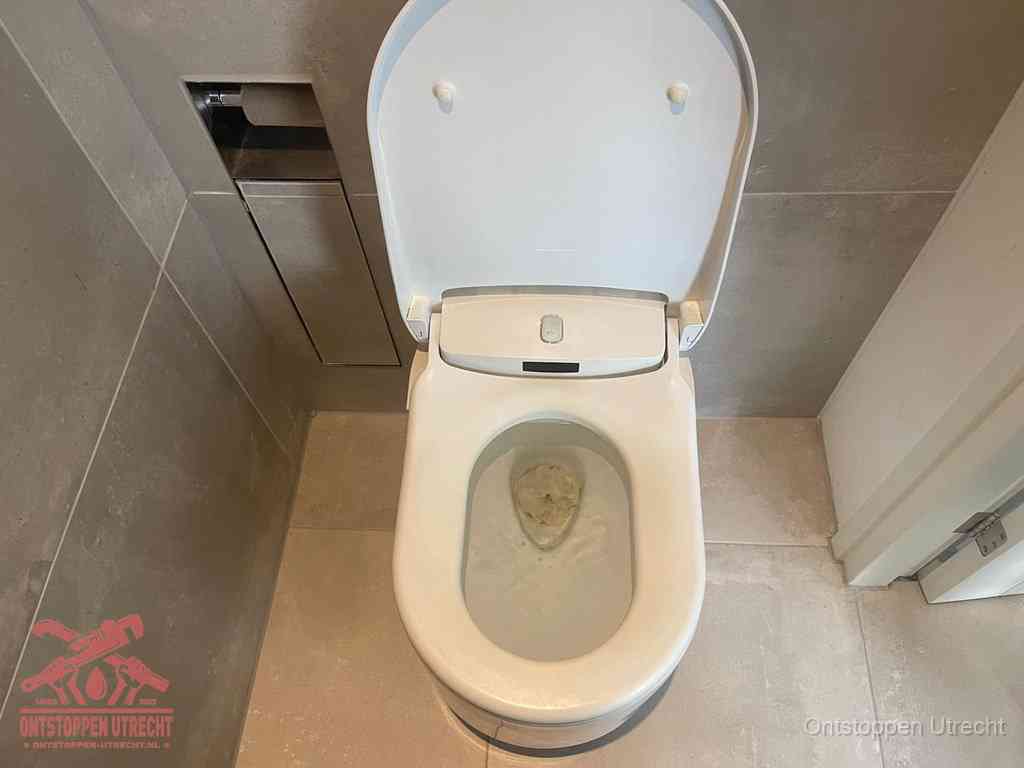 Een wit hangtoilet waarin een prop wc-papier op het water blijft drijven, een duidelijk signaal van een verstopte wc in Utrecht