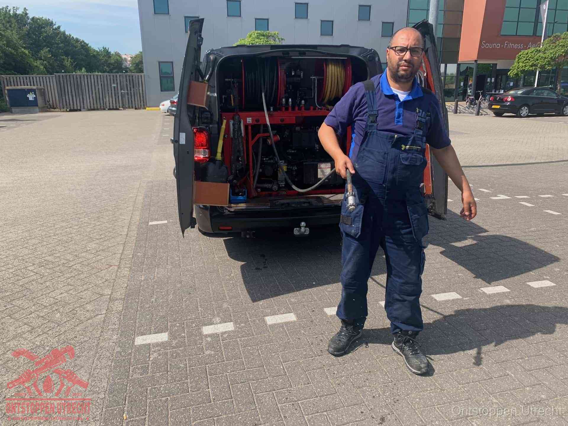 Een monteur bij zijn bestelbus met een hogedruk- en rioolreinigingsunit, klaar om de oorzaak van terugkerende wc-verstoppingen aan te pakken in Utrecht