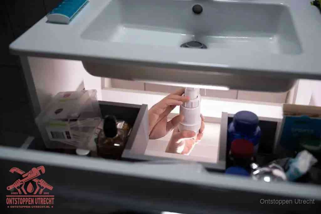 Een pompfles met zeep boven een wastafel in de toiletruimte, de warm water en afwasmiddel-methode om de wc te ontstoppen in Utrecht