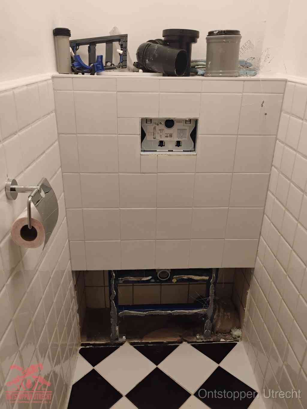 Een toiletruimte waar het hangtoilet en de inbouwreservoir-onderdelen zijn vrijgelegd voor onderhoud, periodiek nazicht voorkomt een wc-verstopping in Utrecht